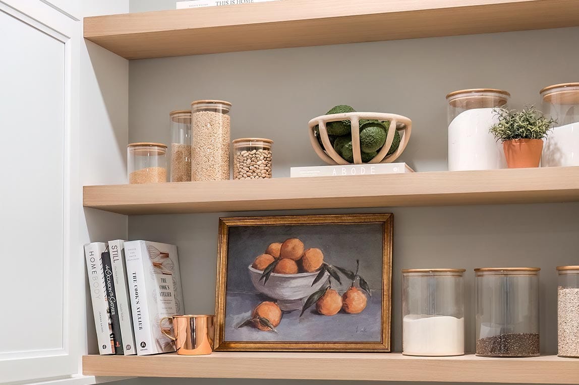 Customized floating shelves for pantry storage in a light wood finish by California Closets