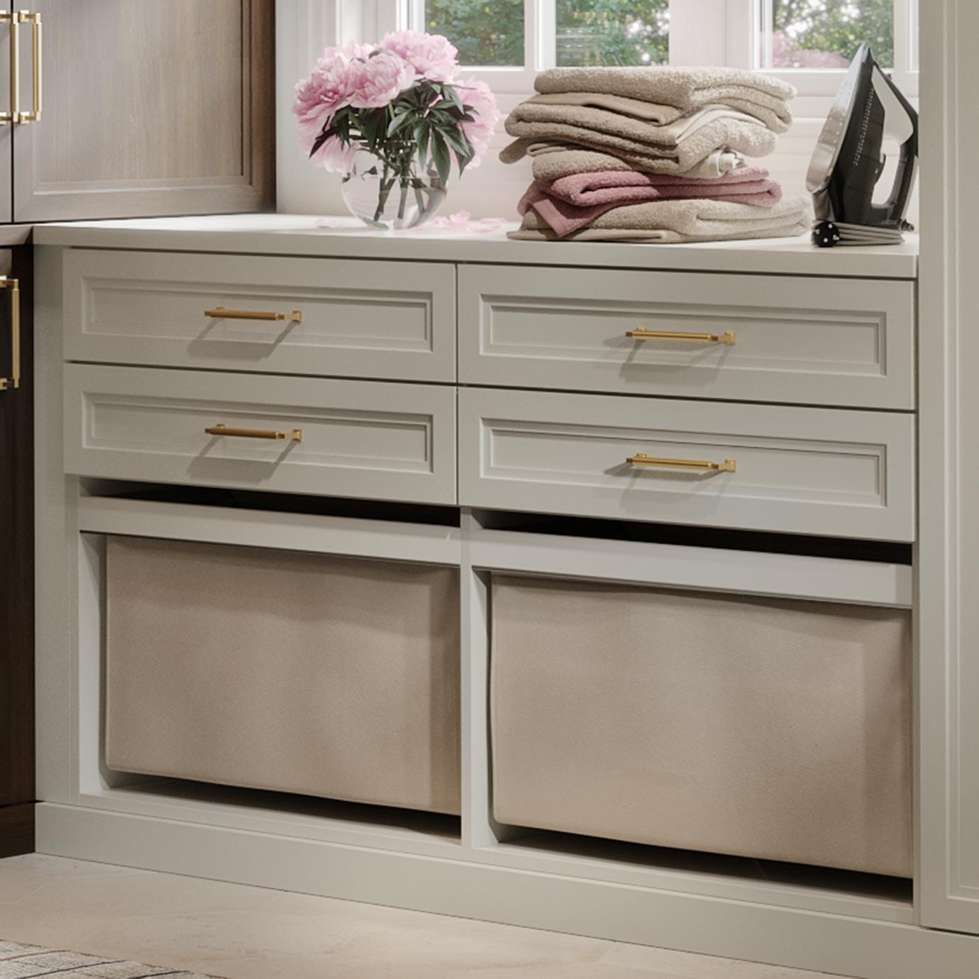 Custom laundry hampers below storage drawers in light finish from California Closets