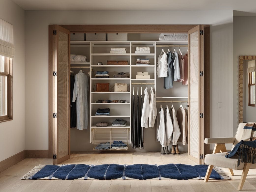 Custom closet designed with open shelves, baskets, long and short hanging area by California Closets
